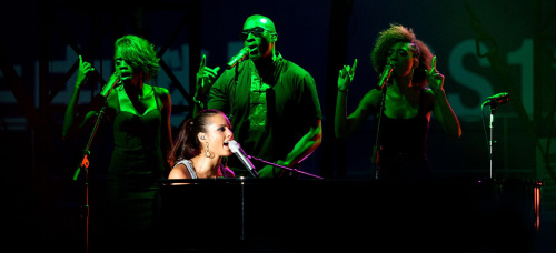 Alicia Keys_ gra na pianinie podczas wykonywania, otoczony przez trzech wokalistów podkład
